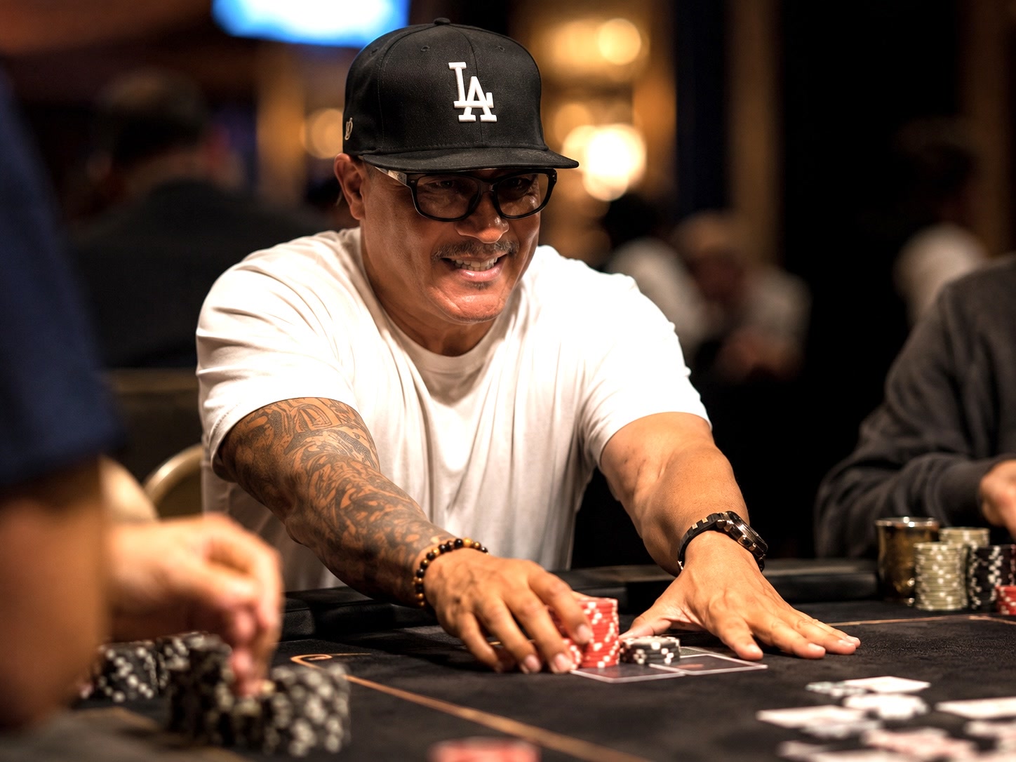 Kevin Lewis at a poker table, moving chips forward during a hand