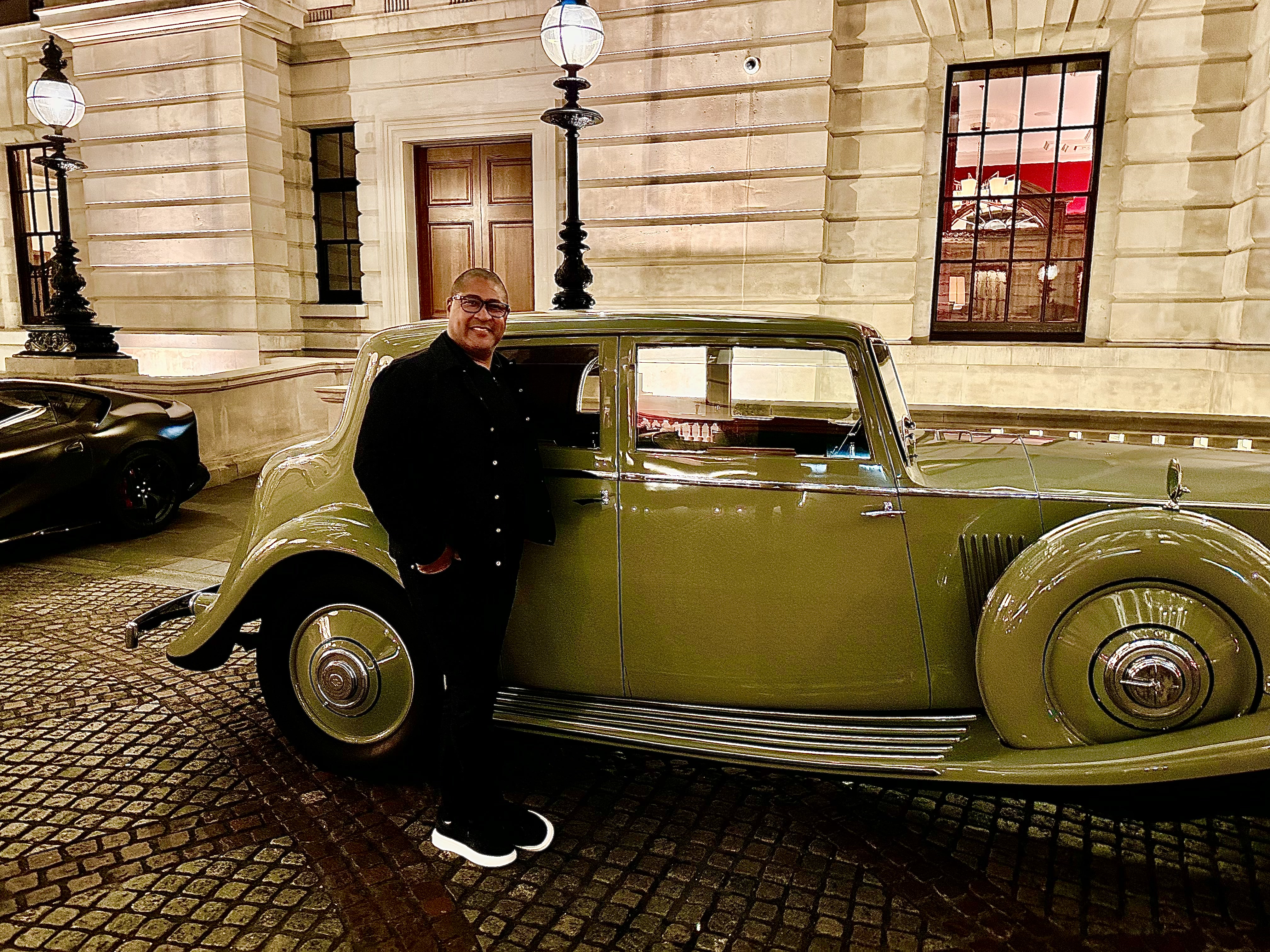 Kevin Lewis beside a vintage saloon car outside a stone building at night